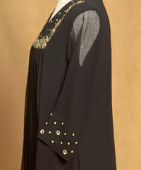 Black garment with gold embellishments on a beige background