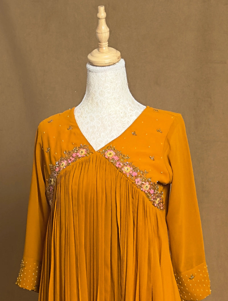 Mustard yellow dress with floral embroidery on a mannequin against a brown background