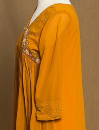 Mustard yellow dress with intricate beadwork on a brown background