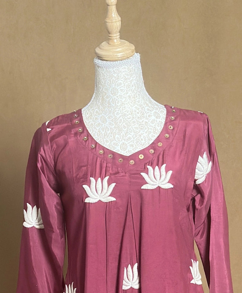 Maroon top with white floral patterns on a mannequin against a beige background