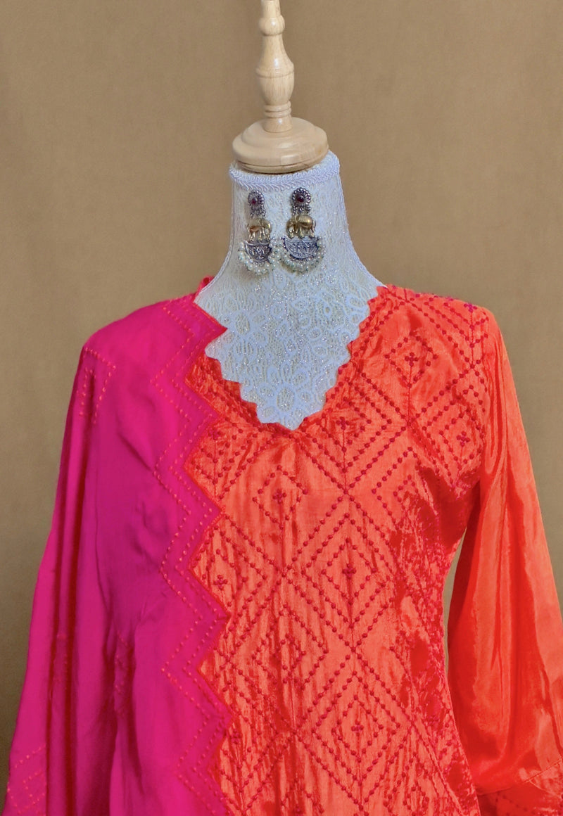 Mannequin wearing a red and pink embroidered top with jewelry on a brown background