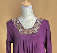 Purple dress with floral embroidery on a mannequin against a beige background