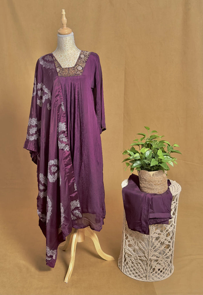 Purple dress with floral patterns on a mannequin and a plant on a stool against a brown background
