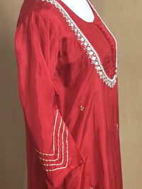 Red garment with white embroidery on a beige background
