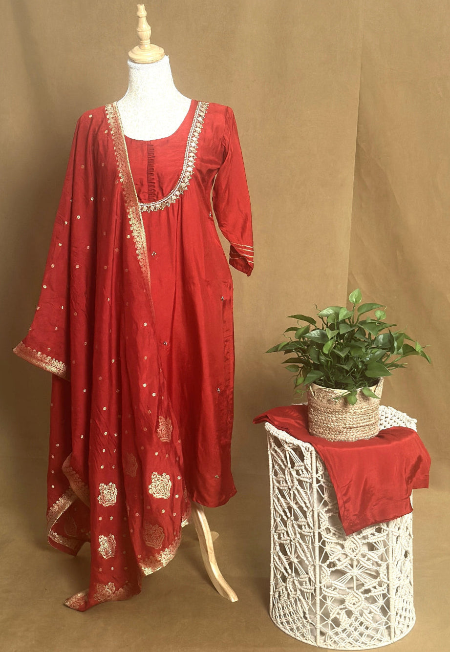 Red traditional outfit with matching dupatta on a mannequin against a brown background