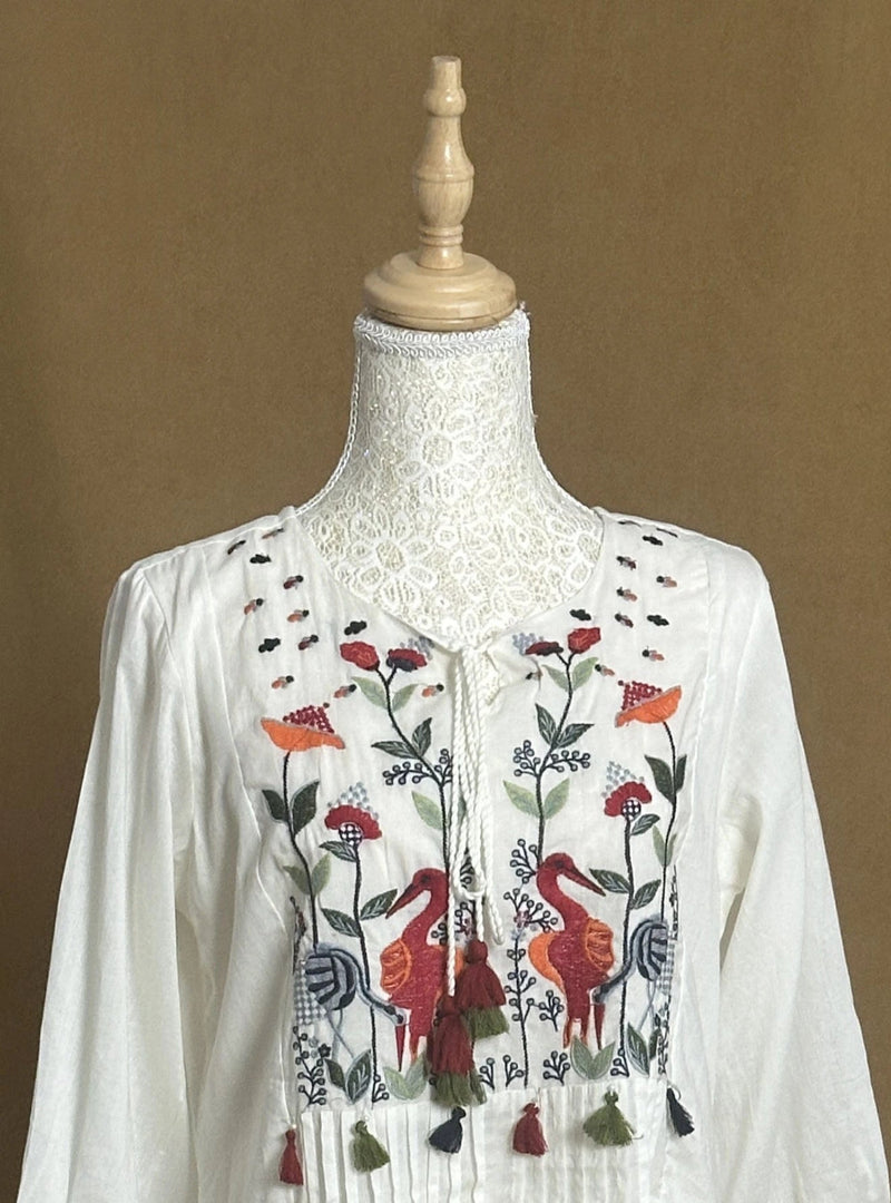 Embroidered blouse on a mannequin against a brown background