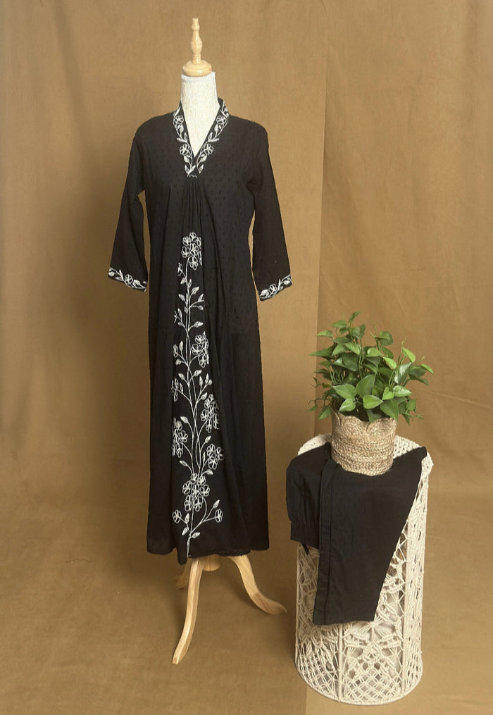 Black dress with white embroidery on a mannequin against a brown background