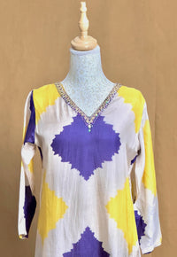 Mannequin wearing a colorful top with purple and yellow patterns on a brown background