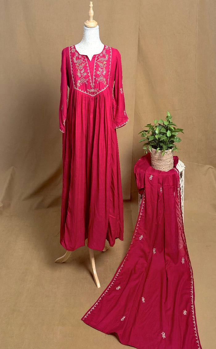 Red embroidered dress on a mannequin with a matching drape against a brown background