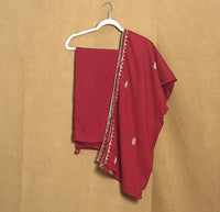 Red saree with white embroidery on a beige background