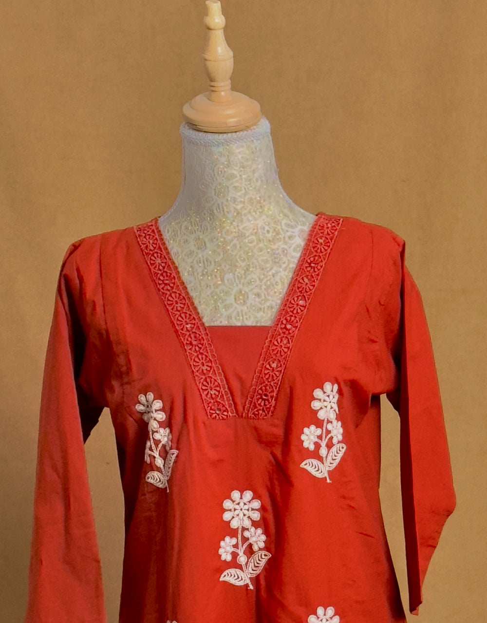 Red embroidered dress on a mannequin against a brown background