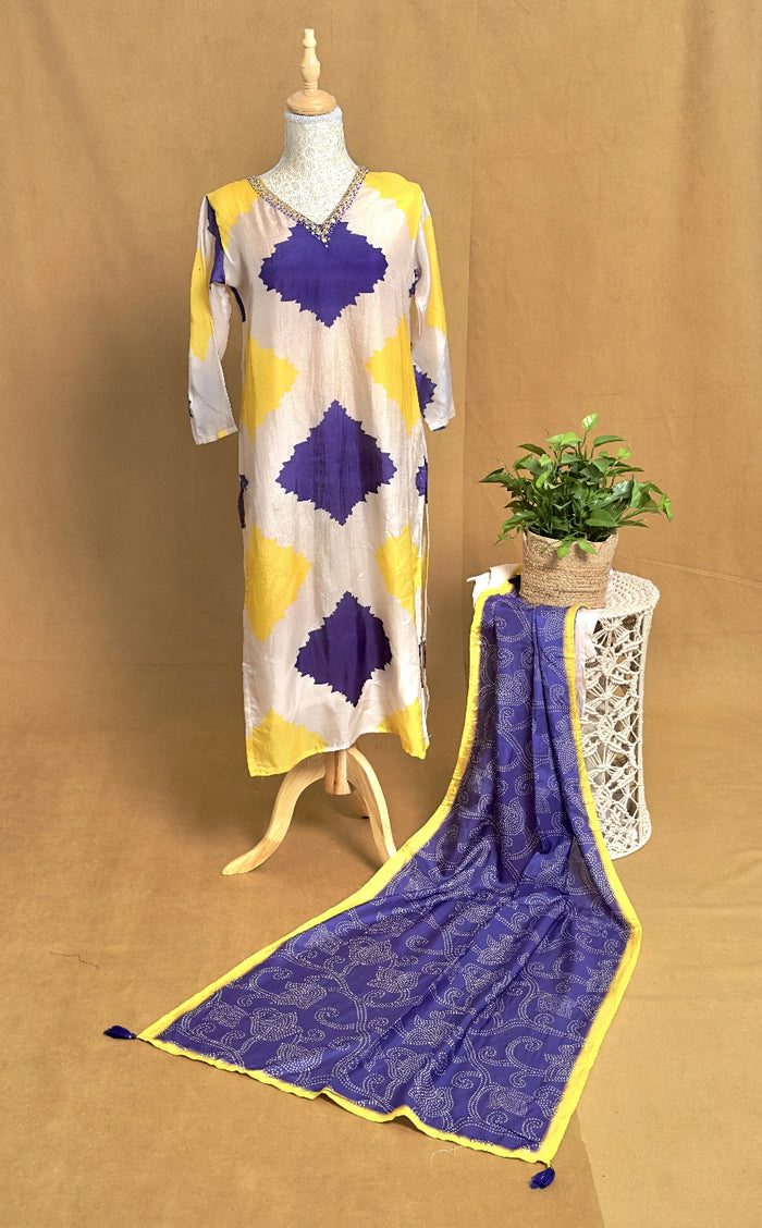 Mannequin wearing a yellow and purple patterned dress with a matching scarf on a brown background.