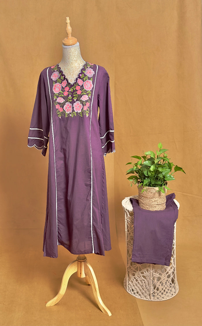 Purple embroidered dress on a mannequin with a plant on a stand against a brown background