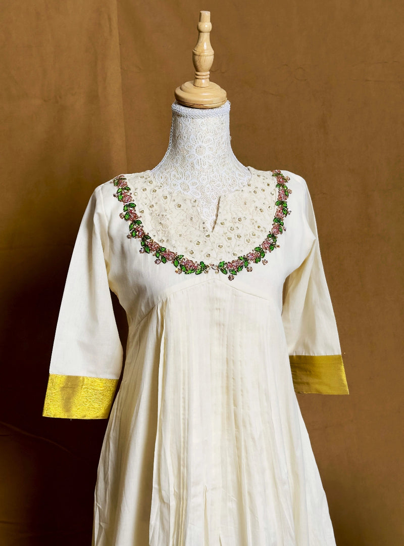 White dress with gold accents on a mannequin against a brown background