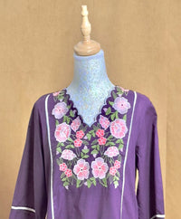 Purple blouse with floral embroidery on a mannequin against a beige background
