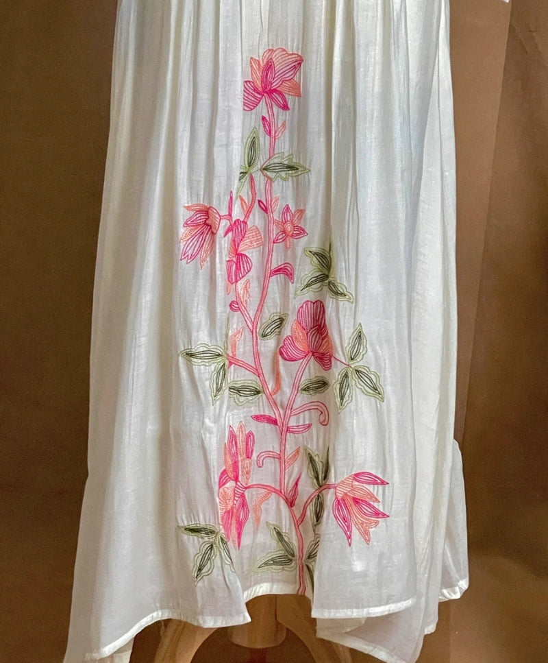 White fabric with pink floral embroidery on a brown background