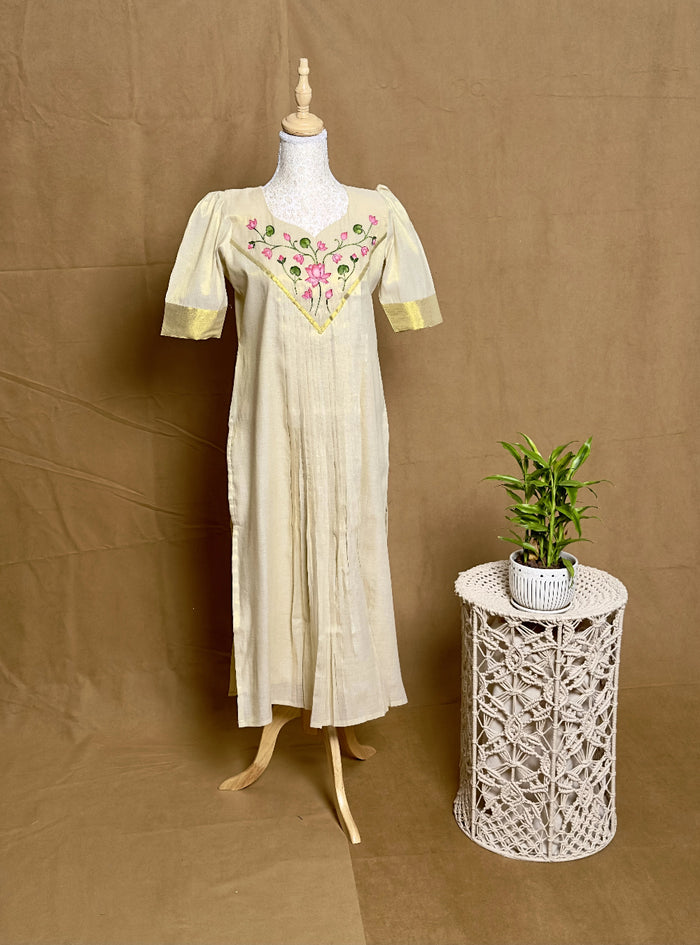 Mannequin wearing a beige dress with floral embroidery on a brown background
