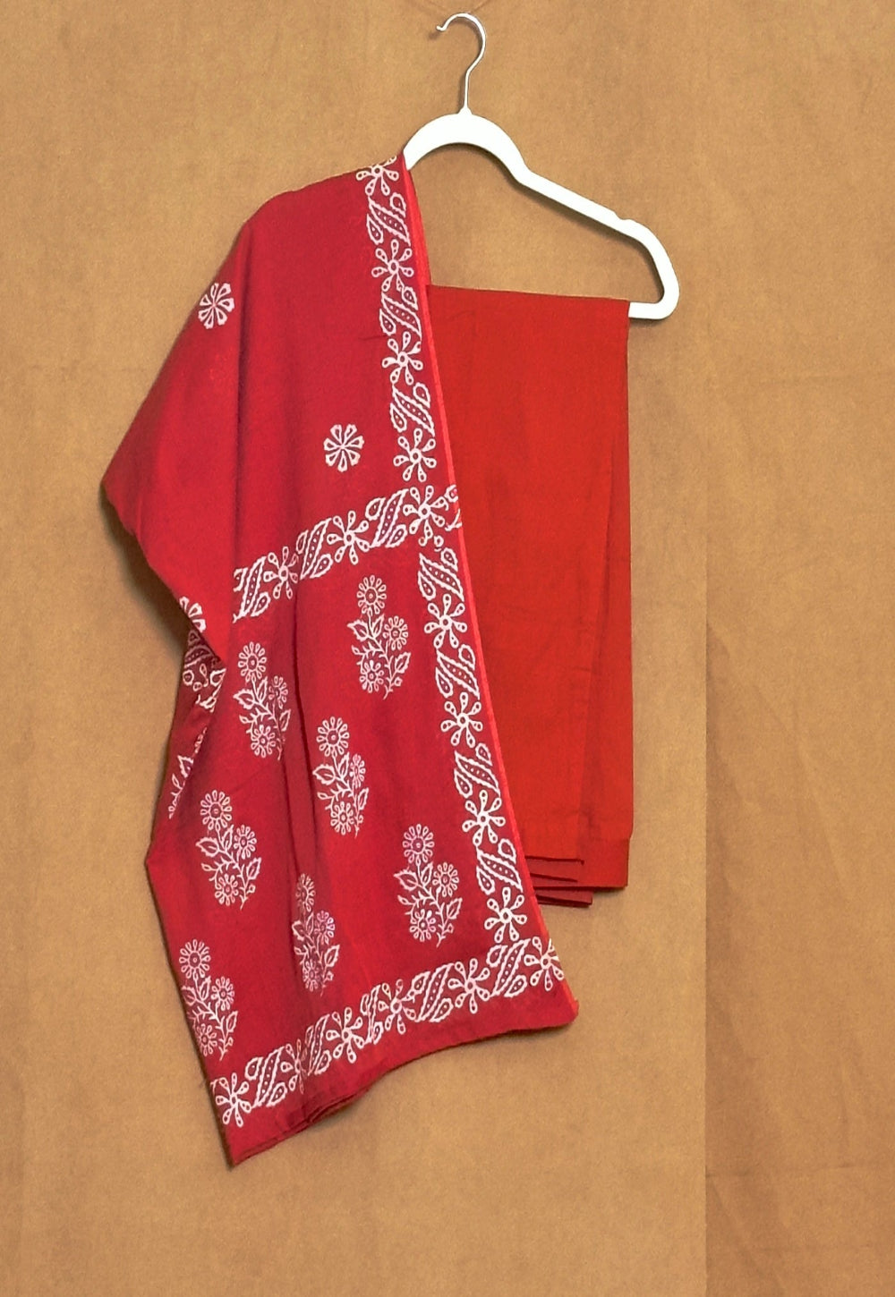 Red fabric with white floral patterns on a beige background