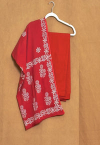 Red fabric with white floral patterns on a beige background