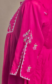 Pink dress with white floral embroidery on a plain background