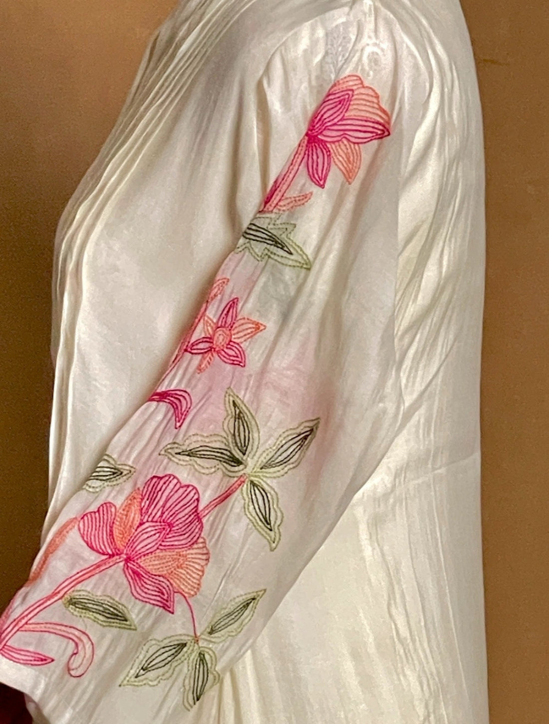 White fabric with pink floral embroidery on a brown background