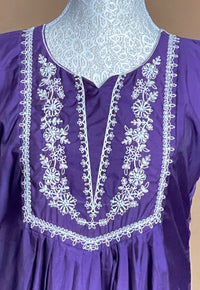 Purple dress with white embroidery on a mannequin against a beige background