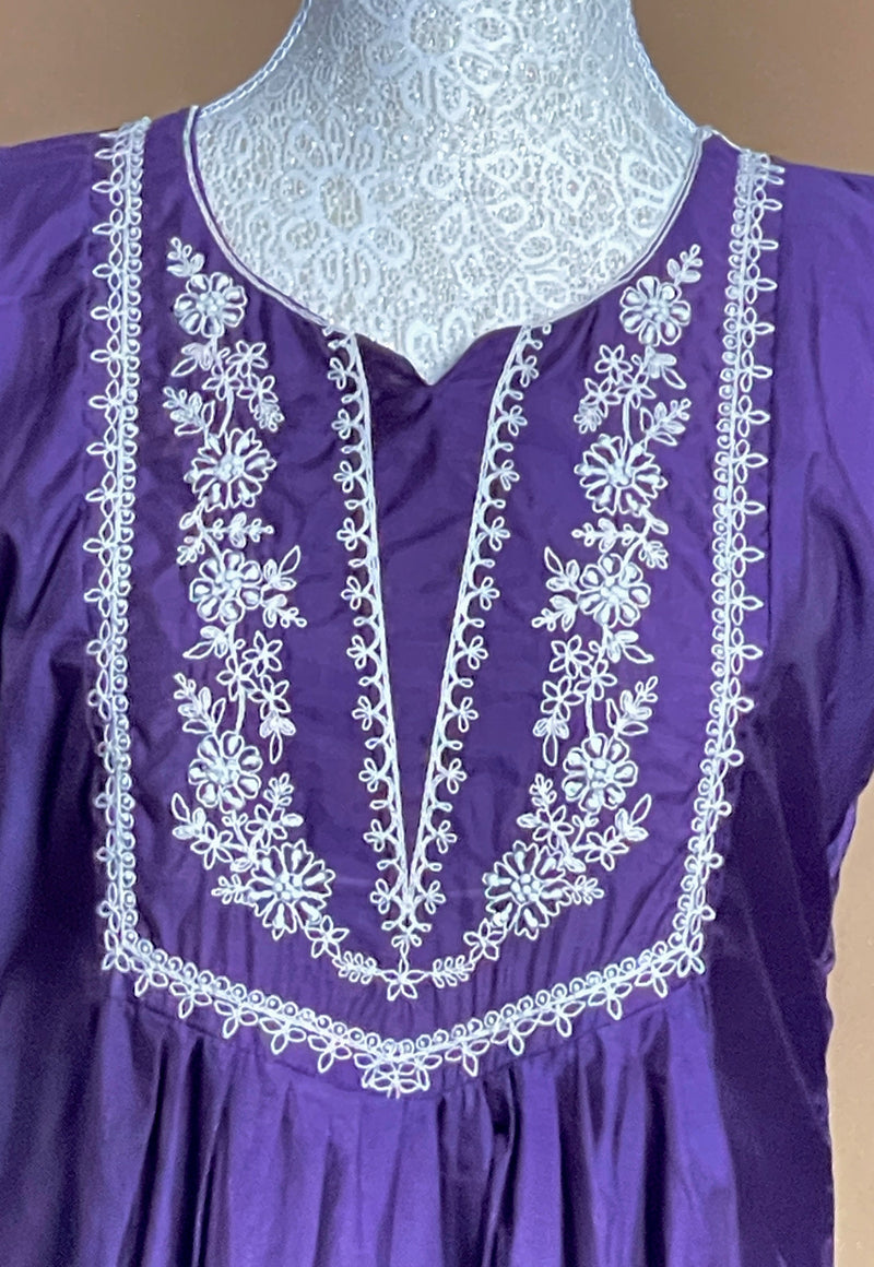 Purple dress with white embroidery on a mannequin against a beige background