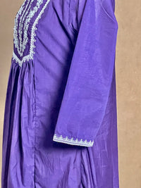 Purple dress with white lace details on a beige background
