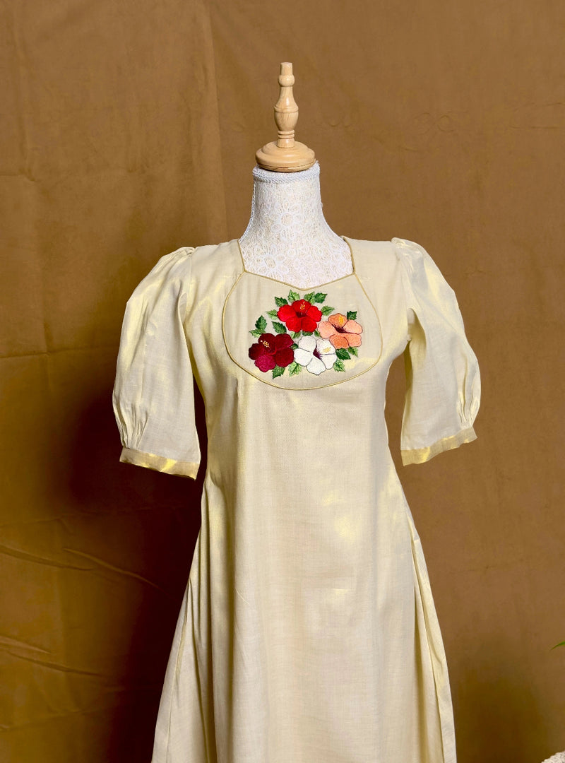 Vintage-style dress with floral embroidery on a mannequin against a brown background