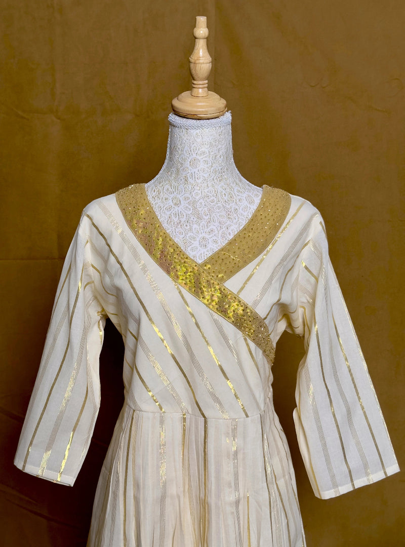 White dress with gold accents on a mannequin against a brown background
