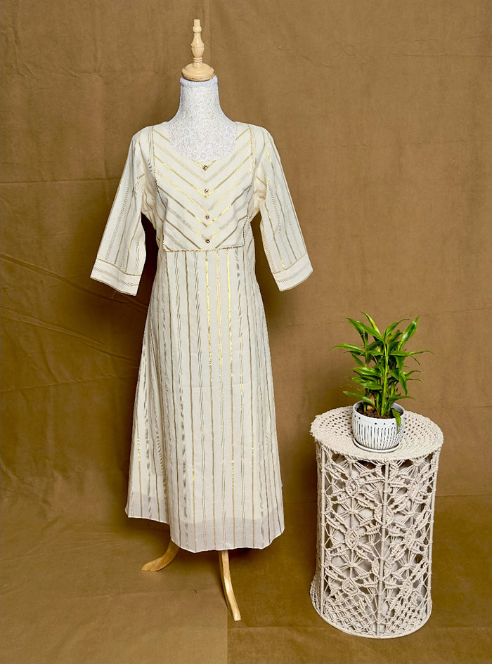 Vintage-style dress on a mannequin next to a decorative side table with a plant against a brown background