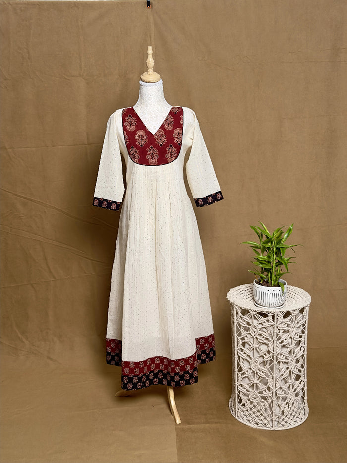 White dress with red and black patterns on a mannequin against a brown background